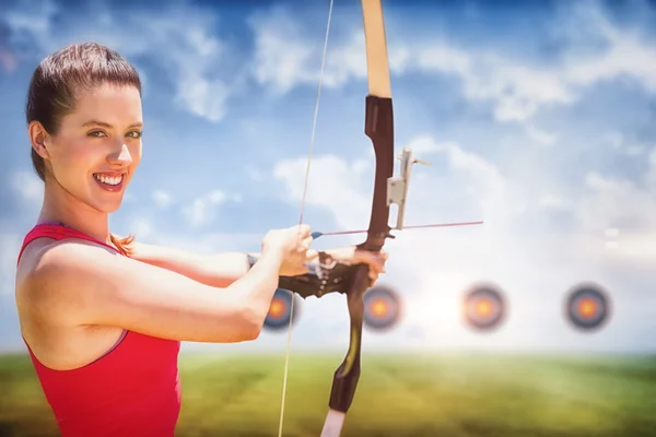 Sportswoman smiling and practising archery