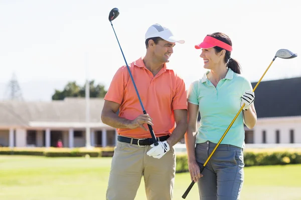 Happy couple holding golf clubs