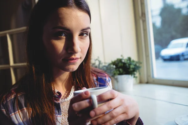 Woman sitting with coffee by window