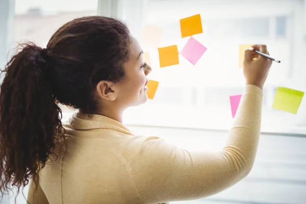 Businesswoman writing on adhesive notes