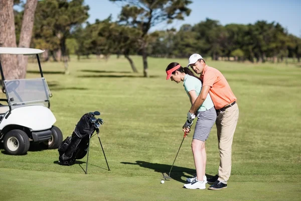 Man teaching woman to play golf