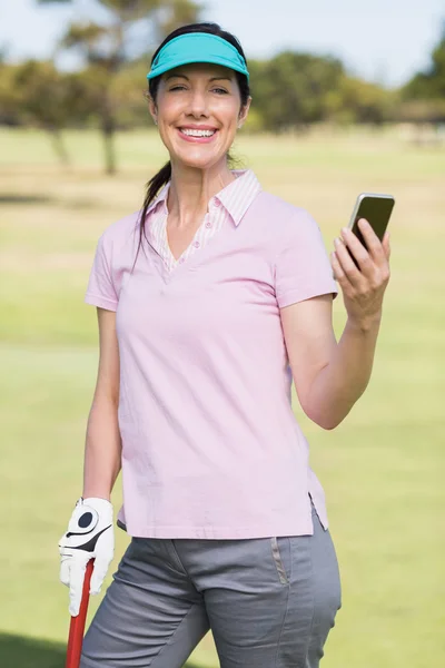 Smiling golfer woman using phone