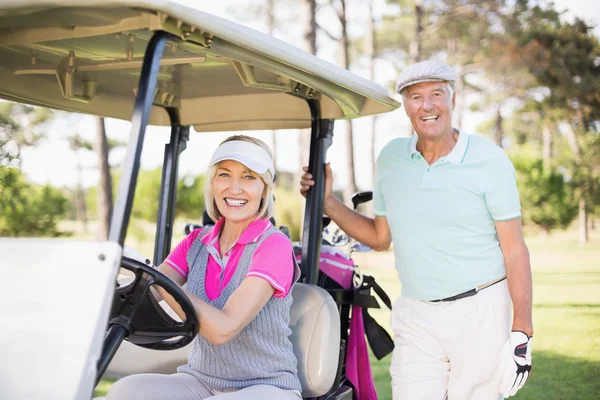 Mature couple sitting in golf buggy
