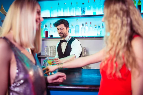 Bartender serving drinks to female customers