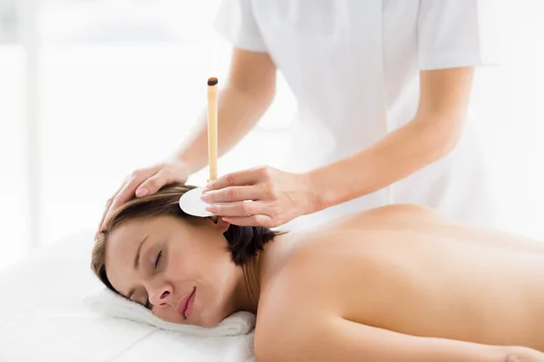 Woman receiving ear candle treatment
