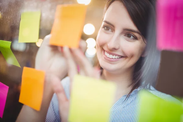 Businesswoman writing on sticky notes