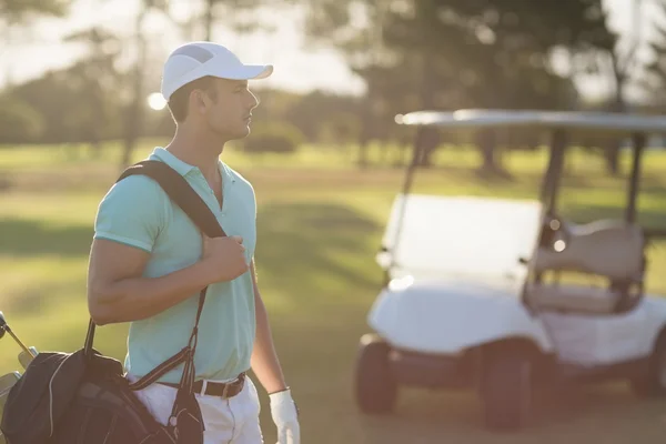 Young golf player carrying bag