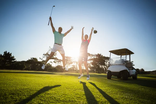 Golf player couple with arms raised