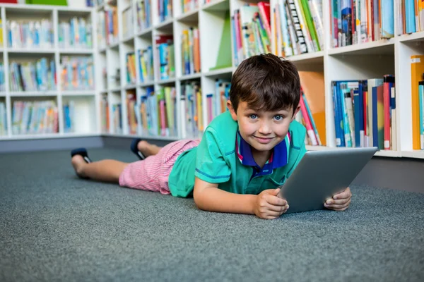 Boy using digital tablet in school library