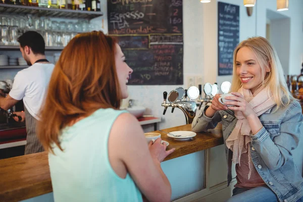 Woman talking to friend at cafe counter