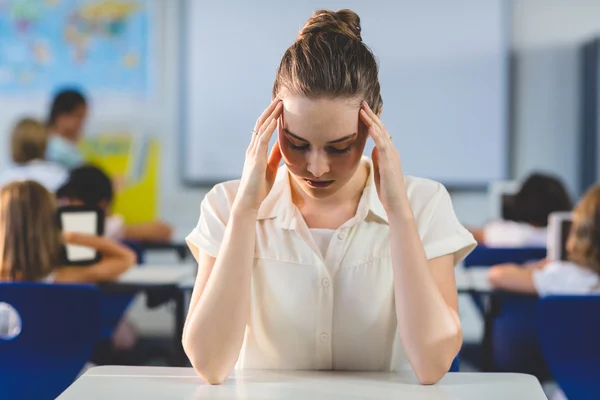 Depressed female teacher touching her head