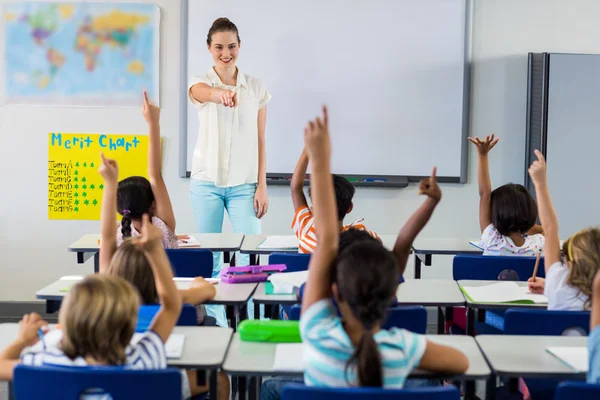 Teacher pointing students with raised hands