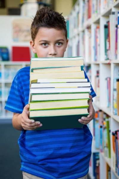 Boy holding books in school library