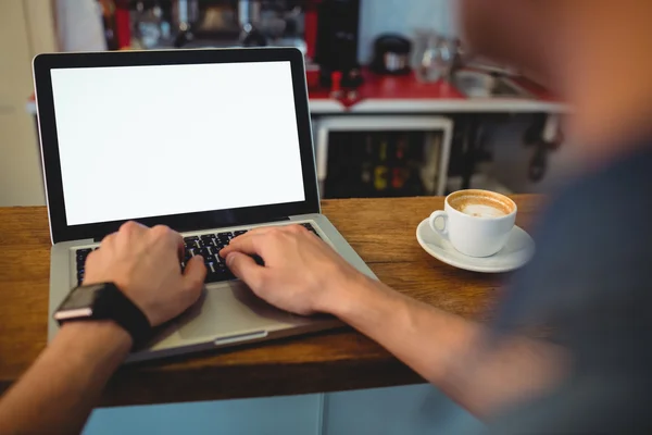 Customer typing on laptop at cafe