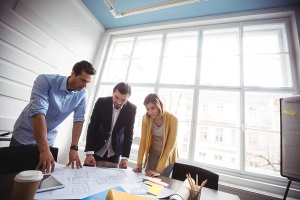 Business people looking at blueprint on table