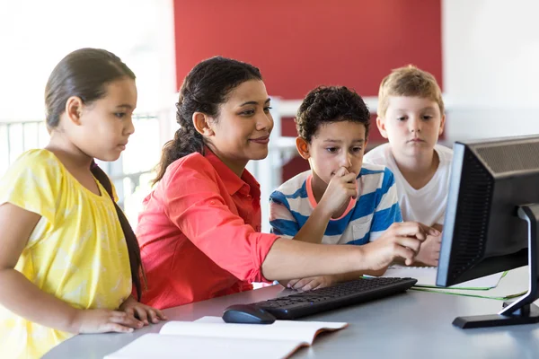 Female teacher teaching computer to children