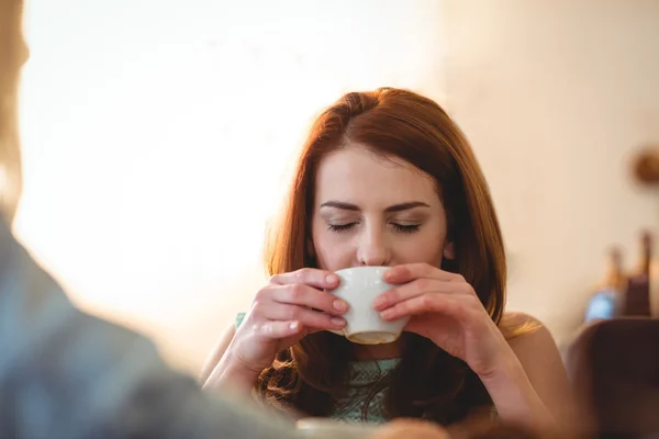 Woman sipping coffee with friend