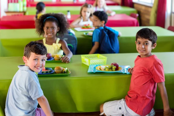 Cute schoolchildren having meal