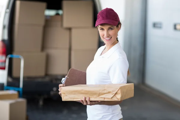 Delivery woman is holding cardboard box and smiling