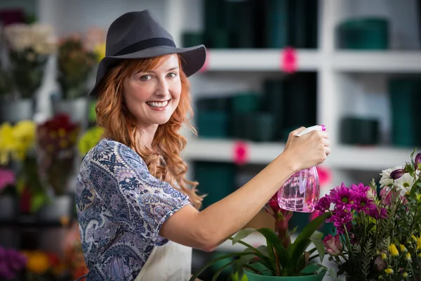 Smiling florist spraying water on flowers