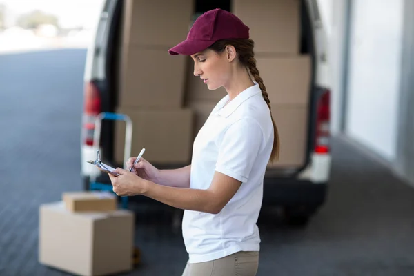 Delivery woman is writing something on a clipboard