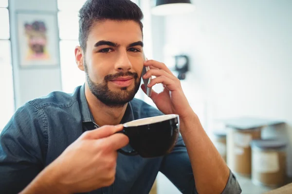 Man talking on mobile phone while having coffee