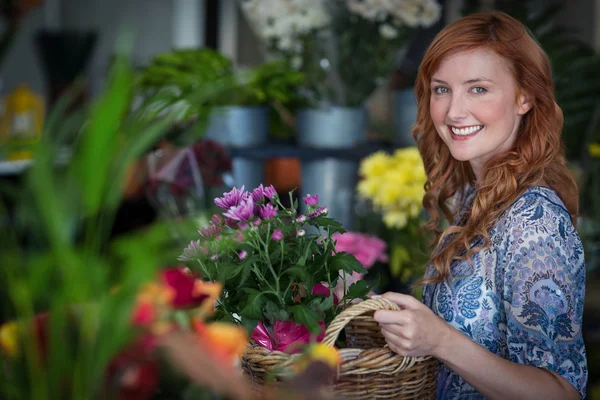 Happy female florist holding basket of flowers