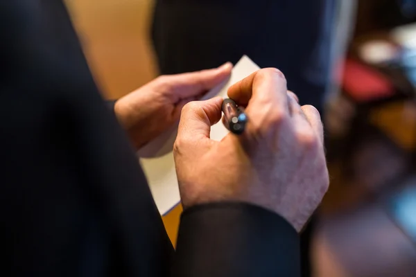 Mid section of waiter writing order on notepad