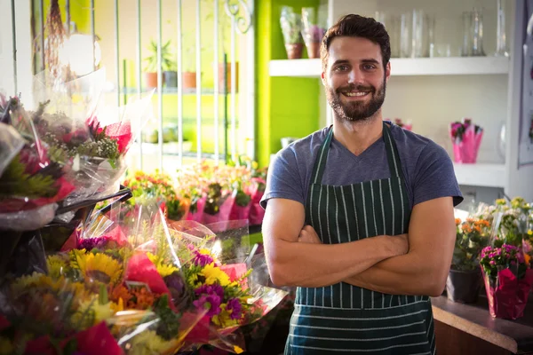 Male florist with arms crossed at his flower shop