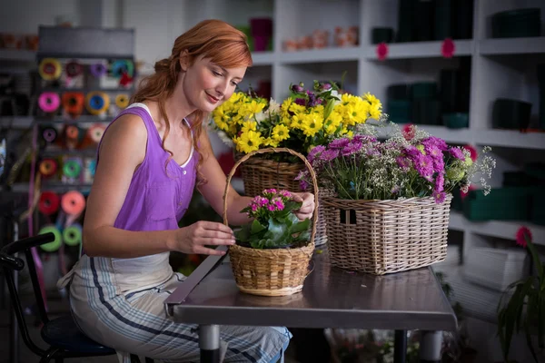 Female florist preparing basket of flowers