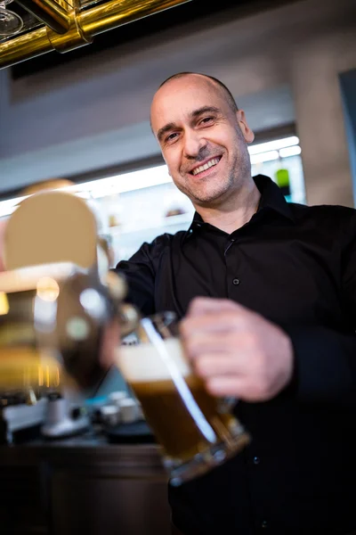 Brewer filling beer in beer glass from beer pump