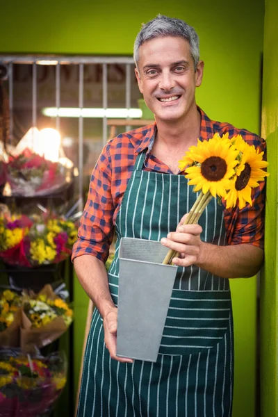 Male florist holding flower vase at flower shop