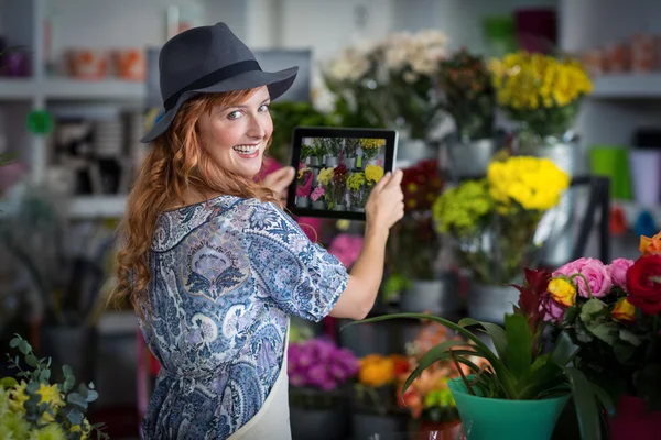 Female florist taking photograph of flowers from digital tablet