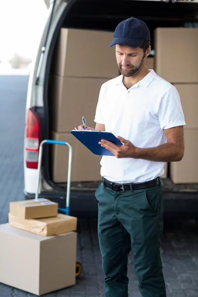 Delivery man is writing something on a clipboard