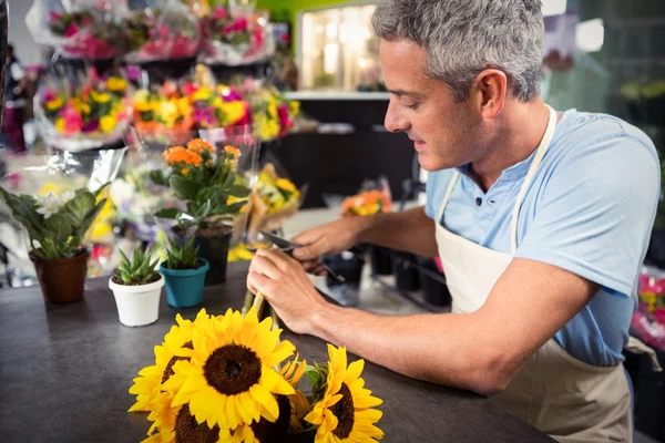 Male florist trimming stems of flowers at flower shop