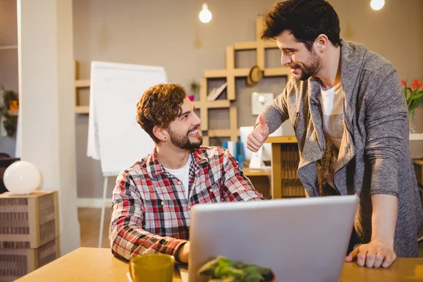 Graphic designer using laptop with his coworker