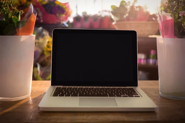 Flower vase and laptop on the wooden table