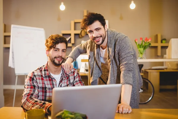 Graphic designer using laptop with his coworker