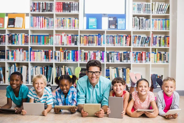 Teacher and kids using digital tablet in library