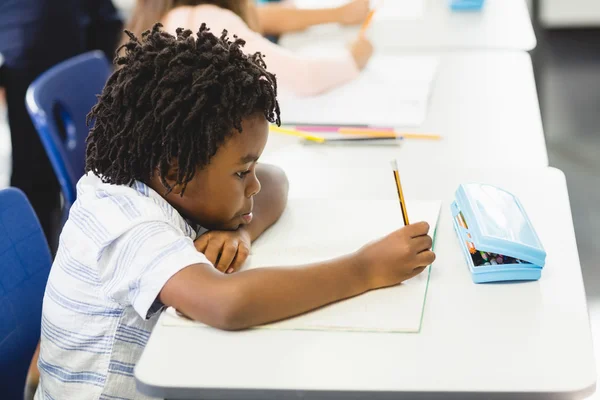 School boy doing homework in classroom