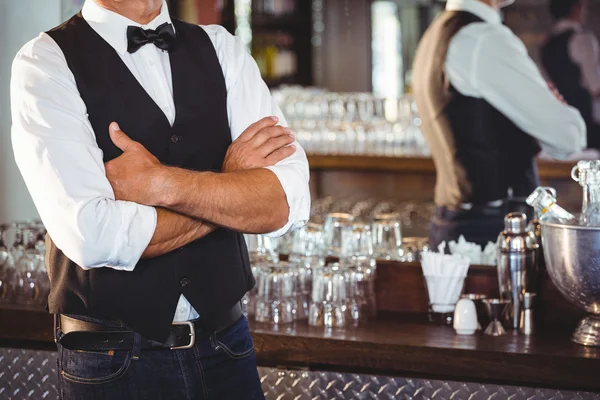 Bartender standing with arms crossed