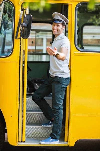 Bus driver standing at the entrance of bus and gesturing