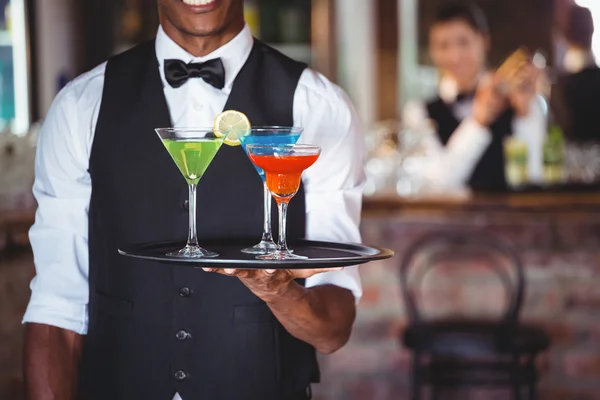 Bartender holding serving tray with cocktail glasses