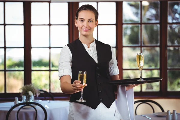 Smiling waitress offering a glass of champagne