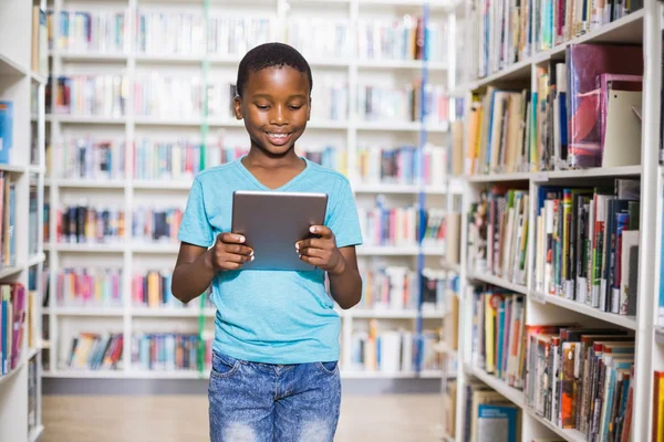 Schoolboy using digital tablet in library