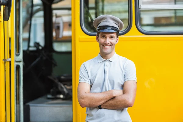 Smiling bus driver standing with arms crossed