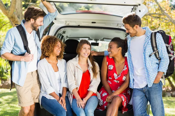 Group of friends on trip sitting in trunk of car
