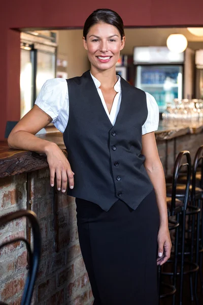 Portrait of waitress standing at bar counter