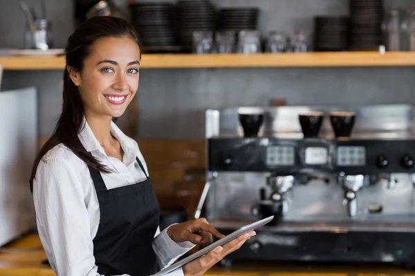 Portrait of smiling waitress using digital tablet
