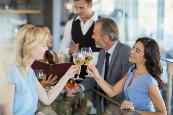 Waiter taking the order while colleagues toasting glasses